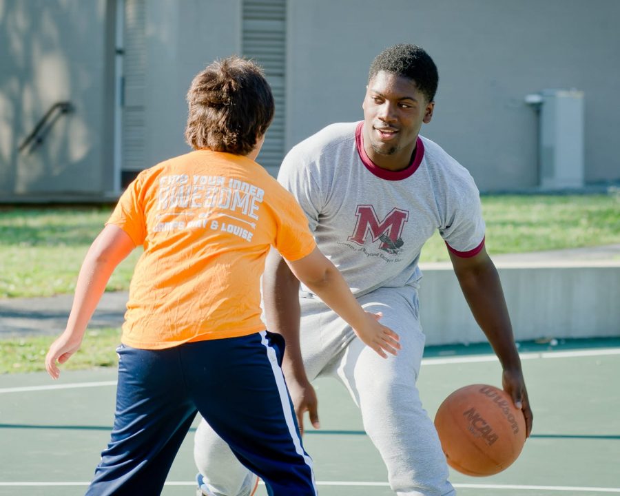 Staff and Airy camper playing basketball