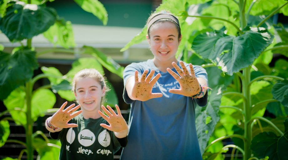 Girls gardening and holding out their hands