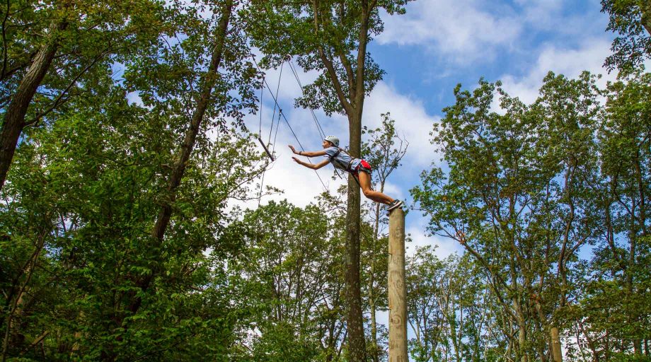 Girl jumping off pole at high ropes course