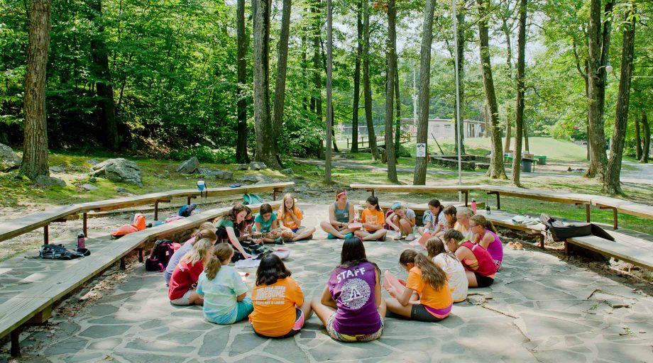 Campers sitting outdoors in a circle playing music