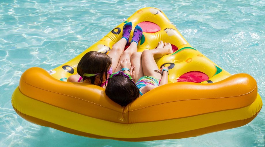 Two girls on pizza floaty in pool