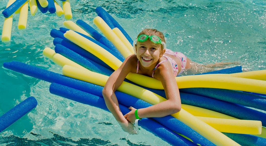 Louise camper in the pool with a bundle of pool noodles